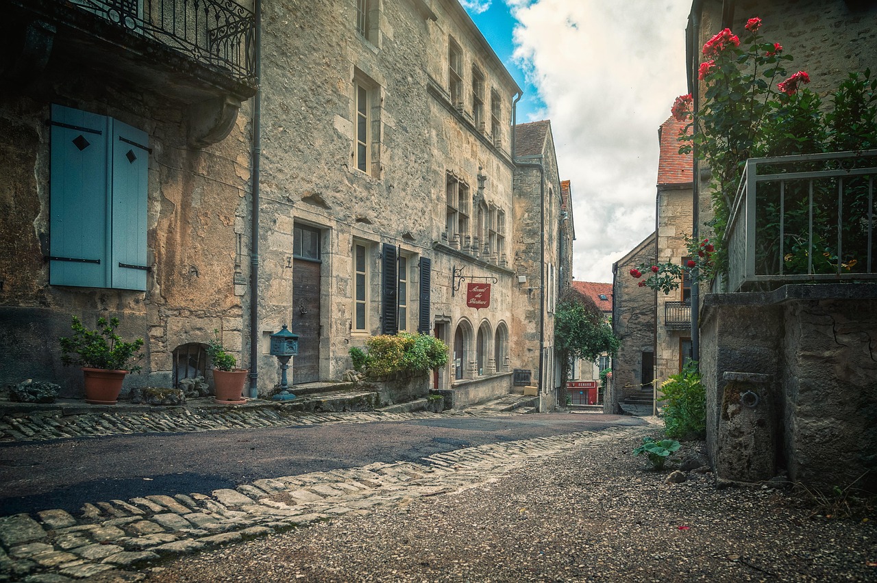 Villaggio francese con case storiche, turisti che esplorano strade pittoresche e atmosfera d'epoca.