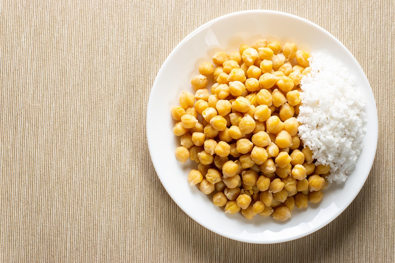 Ciotola di ceci cotti con spezie fresche su un tavolo di legno.