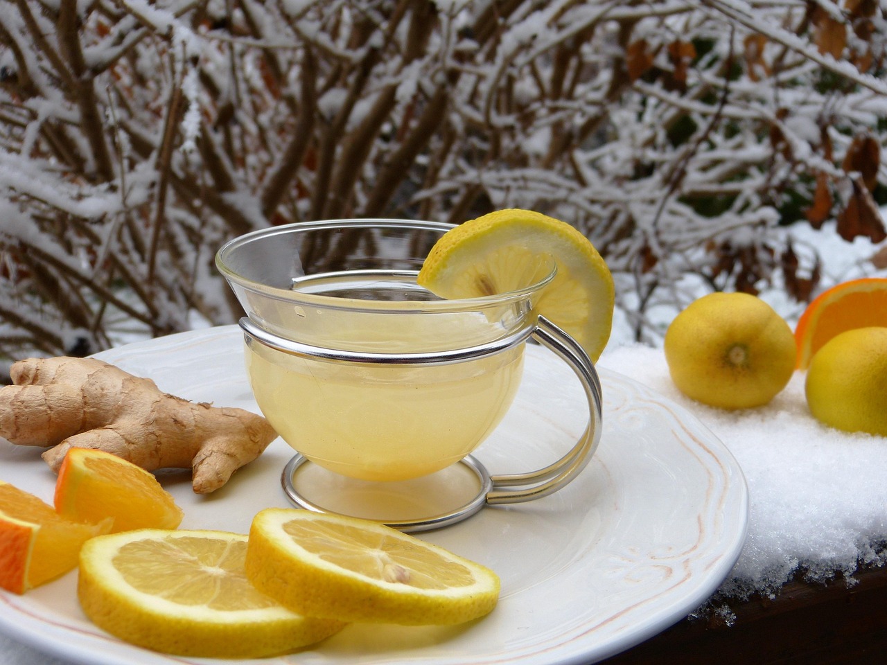 Bouteille d'eau citronnée au gingembre, avec un verre et des tranches de citron, sur une table en bois.